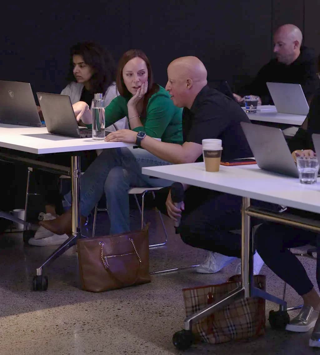 Leo crouched beside an attendee, working through a problem on her laptop