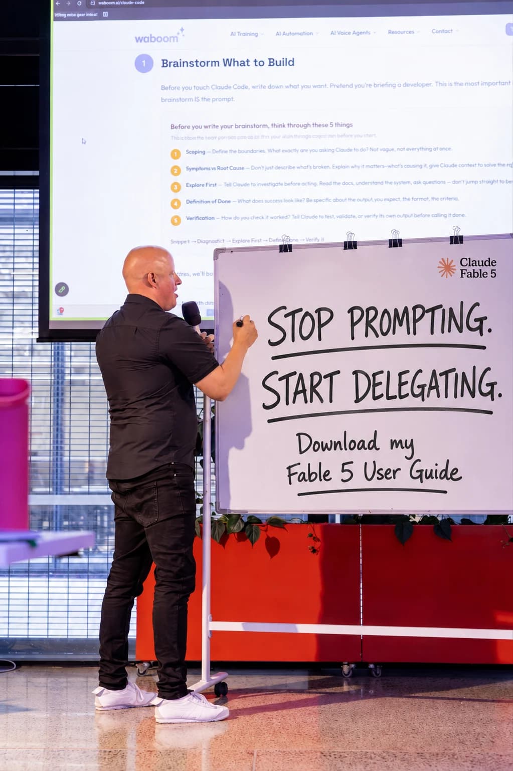 Leo Garcia-Curtis at a Waboom AI workshop writing Stop Prompting, Start Delegating on a whiteboard next to the Claude Fable 5 logo